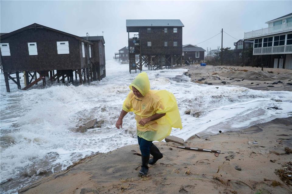 Ein Mann geht während eines Sturmes an einsturzgefährdeten Häusern vorbei.Allison Joyce/FR170575 AP/AP/dpa