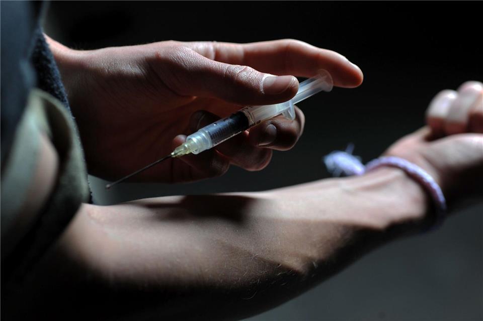 Ein Mann hält eine Heroinspritze an seinen Arm. (Symbolbild)picture alliance / dpa