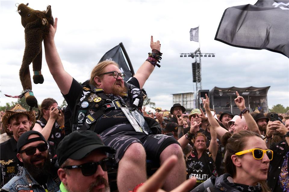 Ein Mann in einem Rollstuhl wird beim Crowdsurfen durch die Menge getragen.Marcus Golejewski/dpa