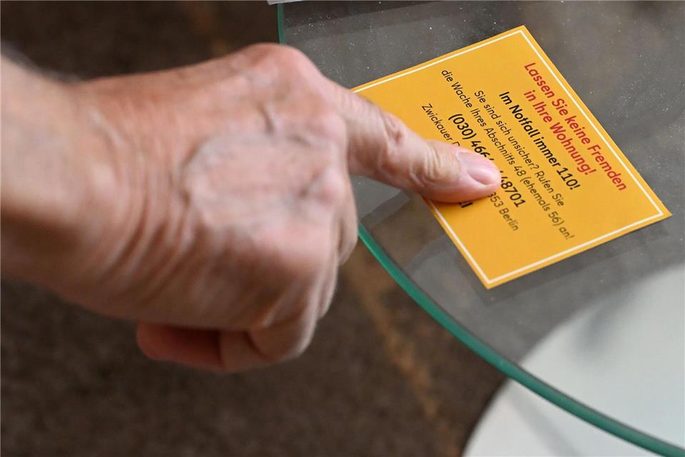 Ein Mann nimmt einen Flyer der Berliner Polizei entgegen.Michael Brandt/dpa