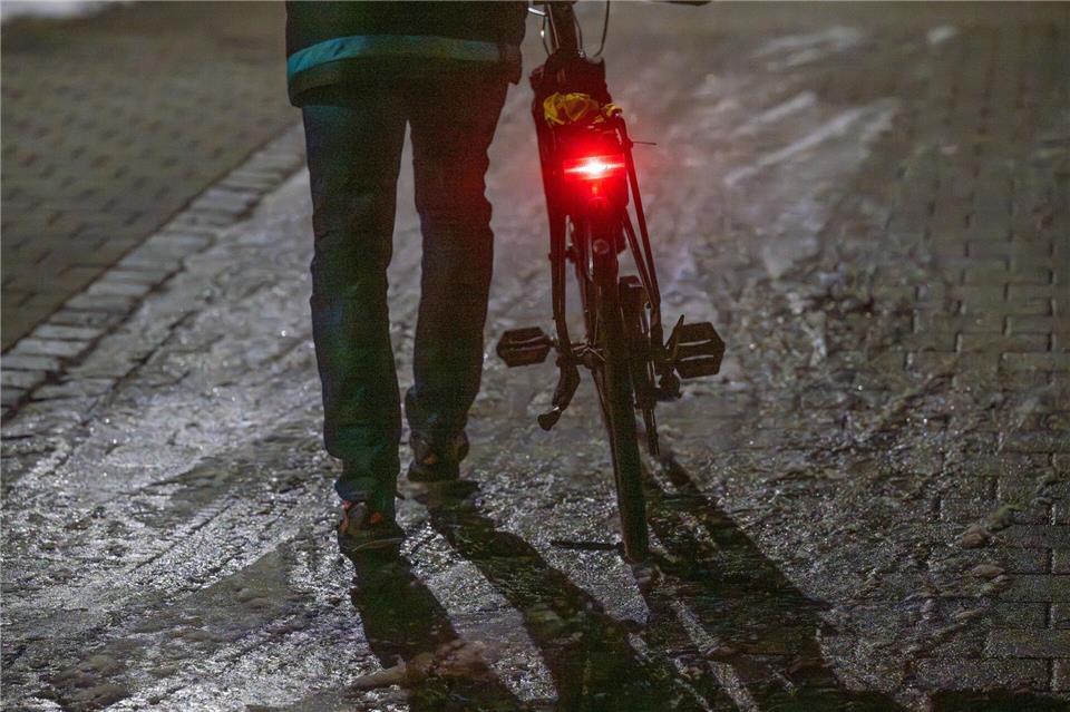 Ein Mann schiebt sein Fahrrad auf einer vereisten Straße.Armin Weigel/dpa