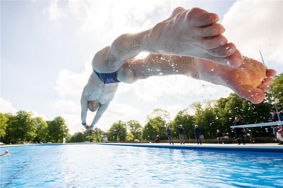 Ein Mann springt zur Eröffnung der Freibadsaison mit einem Kopfsprung ins Becken eines Freibades. (Symbolbild)Julian Stratenschulte/dpa