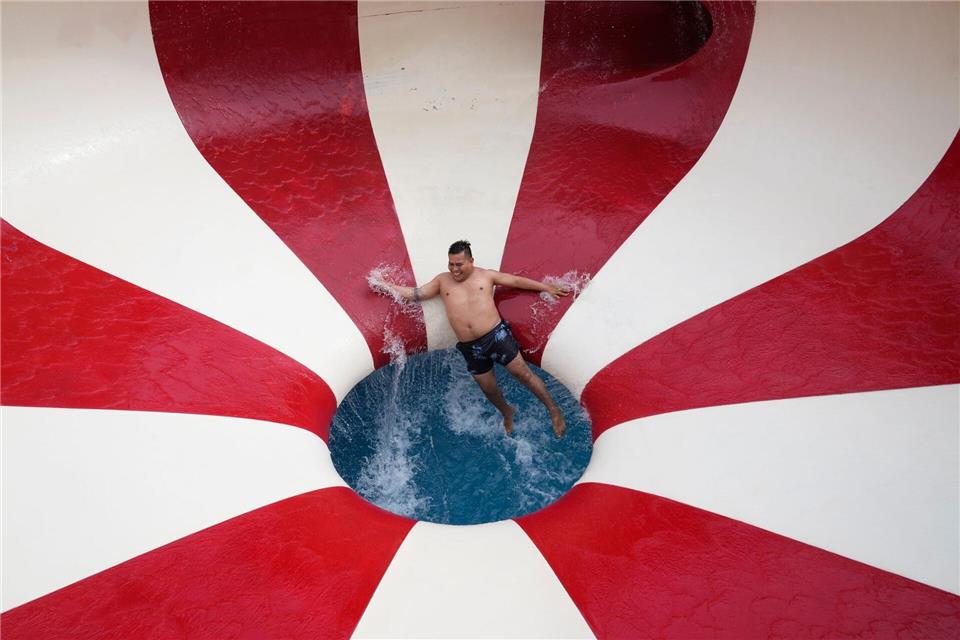 Ein Mann stürzt eine Wasserrutsche in einem öffentlichen Schwimmbad im Stadtteil Puente Piedra außerhalb von Lima hinunter.Martin Mejia/AP/dpa