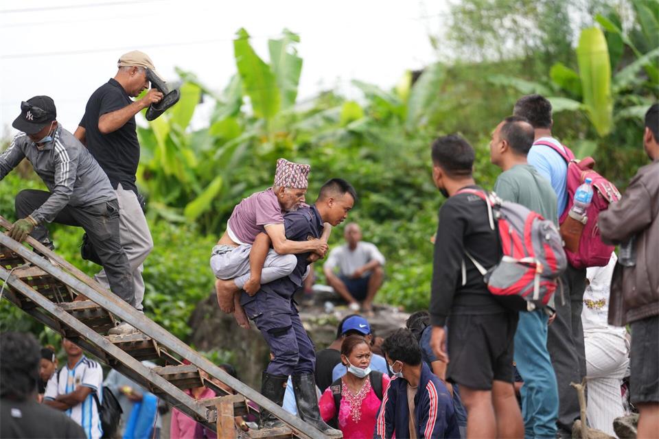 Ein Mann wird im Katastrophengebiet in Nepal von einem Polizisten auf dem Rücken getragen.Rajesh Kumar Singh/AP/dpa