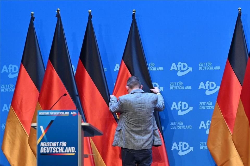 Ein Mann zieht auf dem Podium des AfD-Bundesparteitags in Erfurt eine Deutschlandfahne zurecht.Martin Schutt/dpa