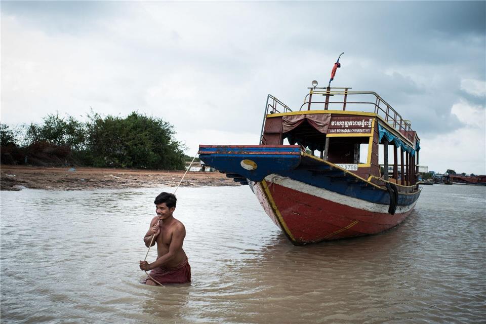 Ein Mann zieht ein Ausflugsboot übers Wasser. Am Tonle Sap ist man bei aller Tradition auch auf die Touristen aus aller Welt eingestellt.Zacharie Scheurer/dpa-tmn