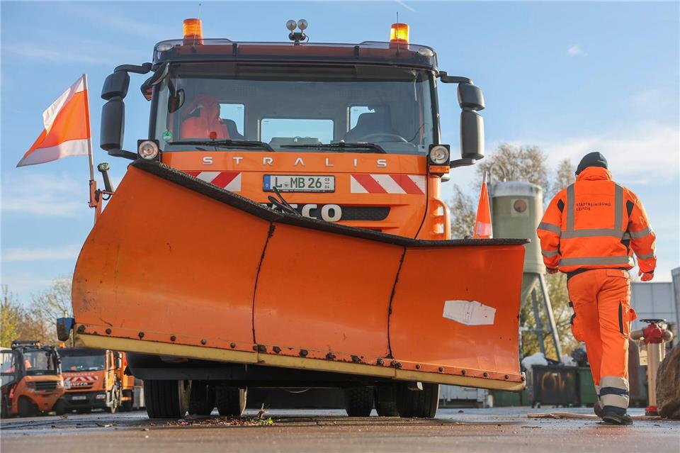 Ein Mitarbeiter der Stadtreinigung Leipzig kontrolliert ein Räumfahrzeug mit Schneepflug.Jan Woitas/dpa