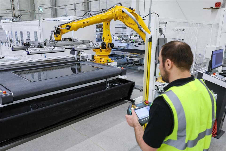 Ein Mitarbeiter überwacht den Zuschnitt von Solarmodulen in der neuen Fabrik von Opes Solar Mobility. Jan Woitas/dpa