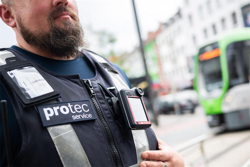 Ein Mitarbeiter von protec steht mit einer Bodycam vor einer einfahrenden Stadtbahn. Der Sicherheitsdienstleiter protec – eine Tochter der hannoverschen Verkehrsbetriebe Üstra – erprobt sie in einem Pilotprojekt.Julian Stratenschulte/dpa