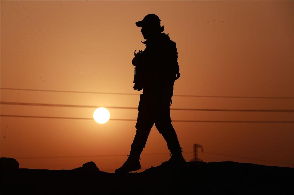 Ein Mitglied der Popular Mobilization Forces läuft an einer Betonmauer entlang.Ameer Al-Mohammedawi/dpa