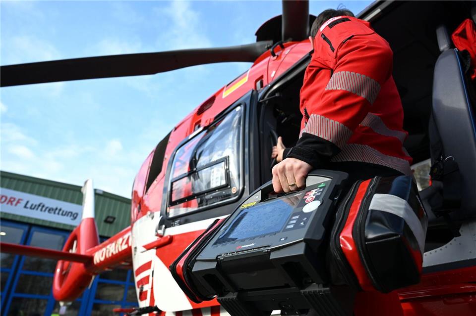 Ein Notarzt steht am hinteren Teil eines Helikopters der Luftrettung und hält einen Defibrillator.Elisa Schu/dpa