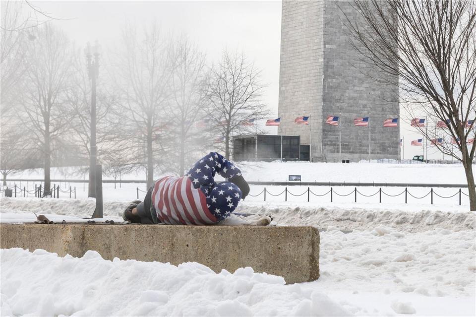 Ein Obdachloser ruht sich nach einem schweren Wintersturm in der Nähe des Washington Monuments auf.Mehmet Eser/SOPA Images via ZUMA Press Wire/dpa