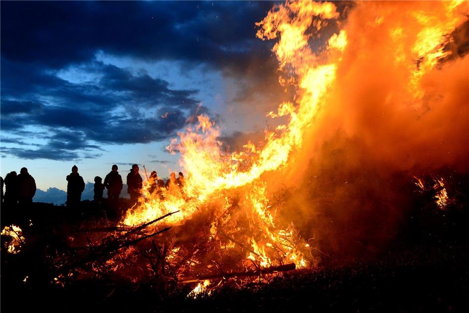 Ein Osterfeuer lodert in der Dämmerung: Der traditionelle Brauch steht zwischen geselligem Frühlingsevent und der Kritik von Natur- und Tierschützern. (Symbolbild)Maurizio Gambarini/dpa