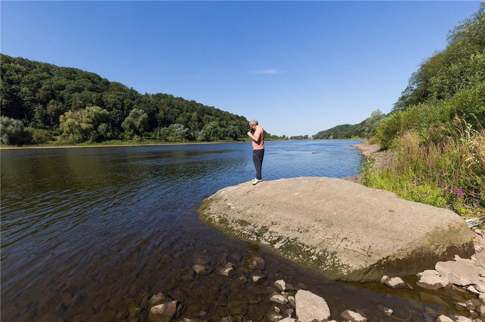 Ein Passant fotografiert Details des Hungersteins von Pirna-Oberposta, der das extreme Niedrigwasser der Elbe aktuell gut zu sehen ist. Die Eintragungen reichen bis ins Jahr 1707 zurück.Jürgen Lösel/dpa
