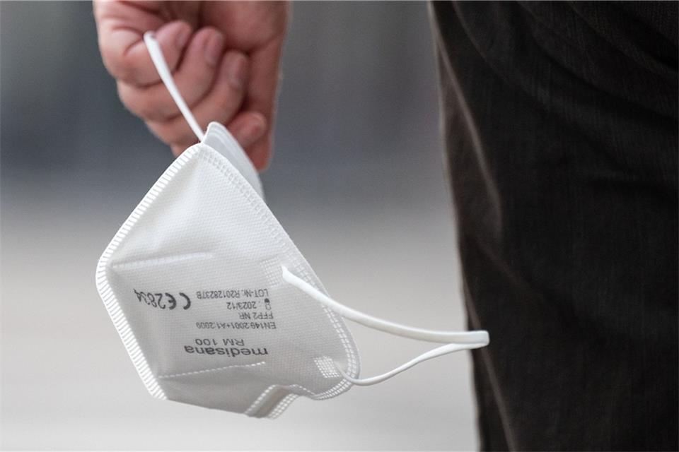 Ein Passant trägt eine FFP2-Maske in der Hand.