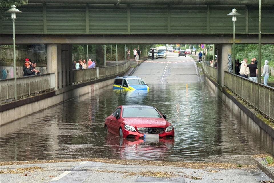 Ein Polizeiauto ist auf einer überfluteten Straße steckengeblieben. Daniel Friederichs/dpa