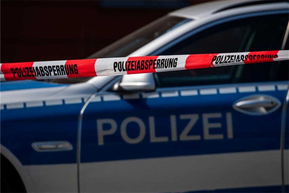 Ein Polizeiauto steht hinter einem Absperrband der Polizei.