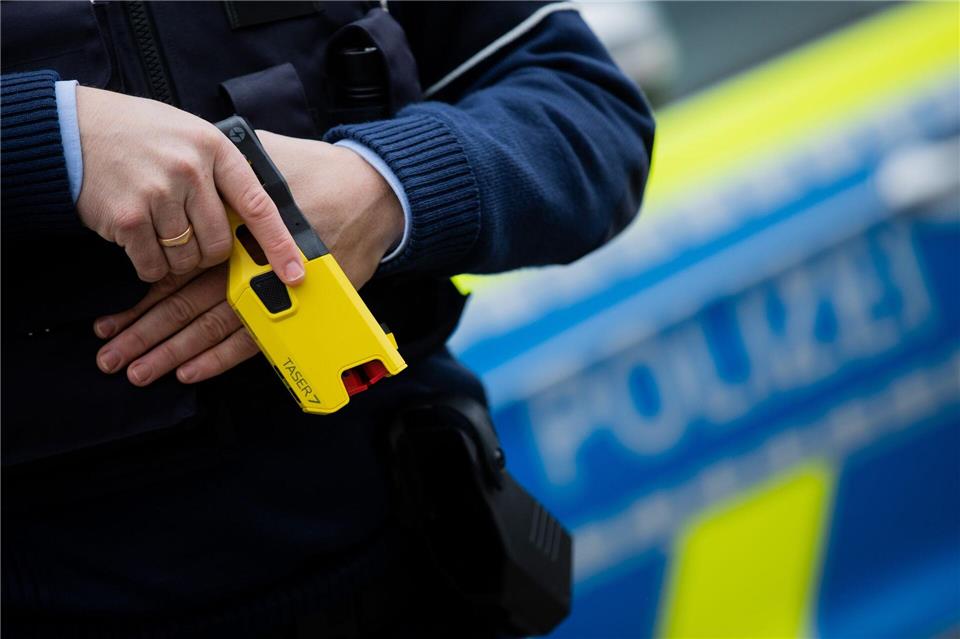 Ein Polizeibeamter demonstriert ein Distanz-Elektroimpulsgerät (DEIG), auch Taser genannt (Archivfoto)Rolf Vennenbernd/dpa