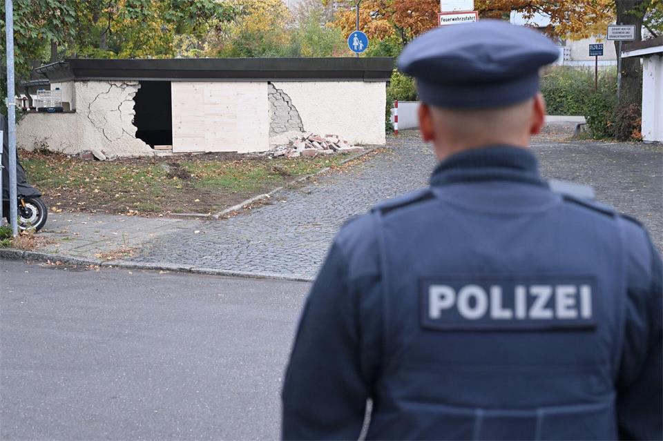 Ein Polizist betrachtet die beschädigte Garagenwand.Felix Hörhager/dpa