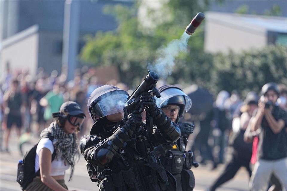 Ein Polizist in Schutzausstattung feuert bei den Protesten gegen den G7 Gipfel in Evian in Frankreich etwas in die Luft. Die Demonstrationen finden in der auf der Schweizer Seite des Genfersee gelegenen Stadt Genf statt.Michael Kappeler/dpa