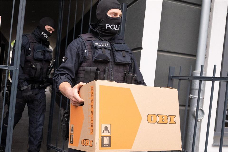 Ein Polizist trägt im Rahmen der Razzia gegen die Schleuser-Bande einen Karton aus einem Gebäude (Archivfoto)Benjamin Westhoff/dpa