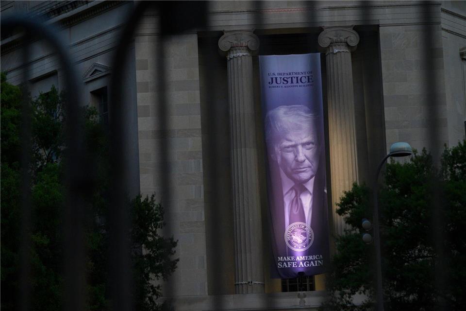 Ein Porträt von US-Präsident Donald Trump ist durch einen Sicherheitszaun am Justizministerium in Washington zu sehen, während in der Nähe das Dinner der White House Correspondents‘ Association stattfindet.Cliff Owen/AP/dpa
