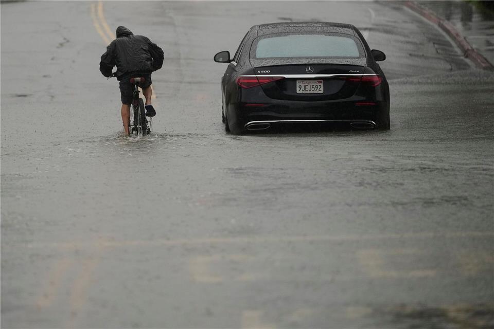 Ein Radfahrer fährt durch eine überflutete Straße.Jeff Chiu/AP/dpa