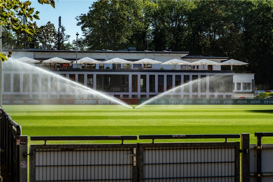 Ein Rasensprenger läuft auf dem Trainingsgelände des Fußball-Bundesligisten 1. FC Köln. Im Hintergrund ist das Geißbockheim zu sehen. Der Ausbau im Grüngürtel der Stadt ist umstritten. Christian Knieps/dpa