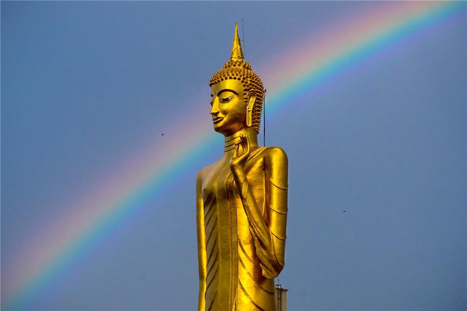 Ein Regenbogen ist hinter der stehenden Buddha-Statue Luang Pho Yai des Wat Buraphaphiram in Roi Et, Thailand, zu sehen.Adryel Talamantes/ZUMA Press Wire/dpa