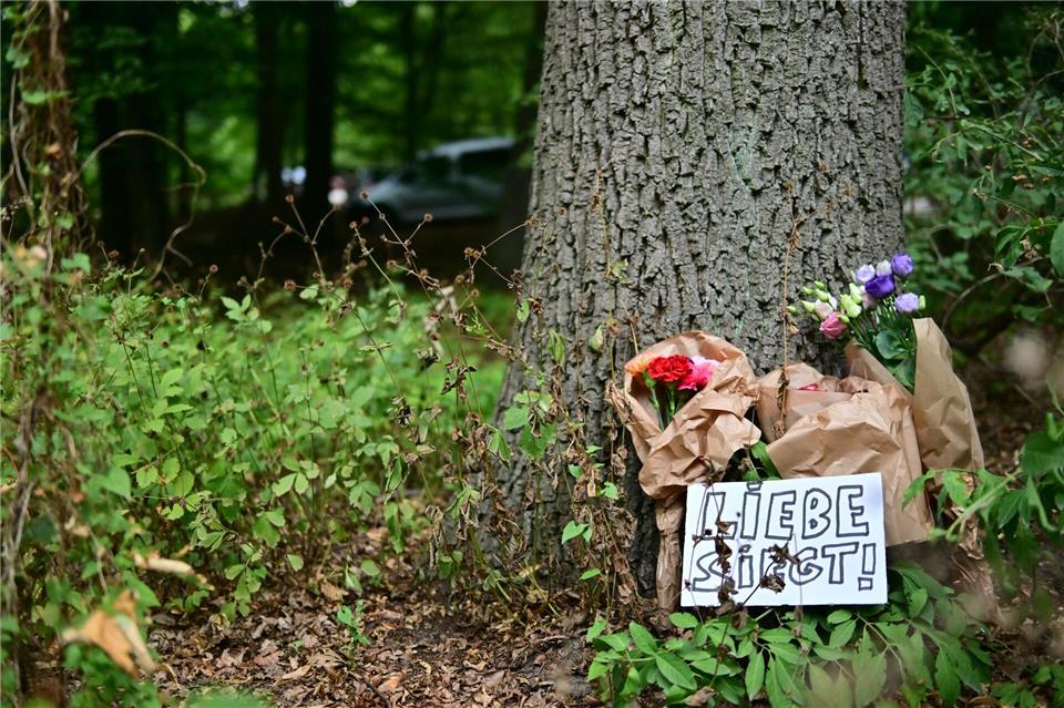 Ein Schild mit der Aufschrift „Liebe siegt!“ liegt vor Blumen an einem Baum, nahe einem abgesperrten Bereich des Tiergartens, wo ein Fahrzeug einen Baum gerammt hatte. Sebastian Gollnow/dpa