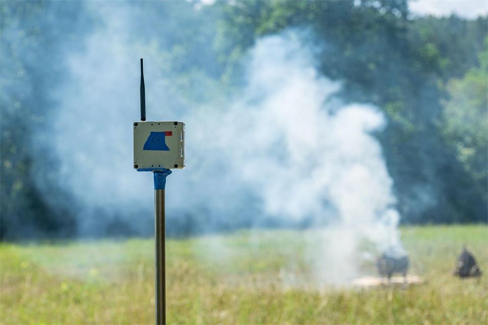 Ein Sensor zur Waldbrandfrüherkennung steht vor einem künstlich erzeugten Brand.Armin Weigel/dpa