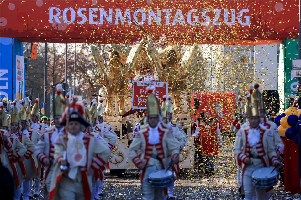 Ein Spielmannszug geht im Konfettiregen vor dem Schriftzug "Rosenmontagsszug" entlang.