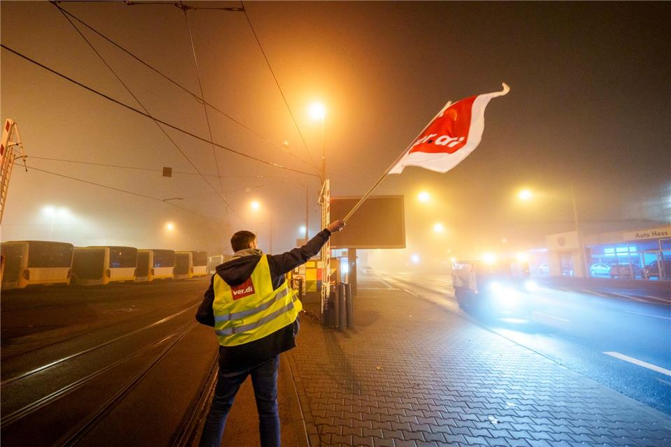 Ein Streikender schwenkt in der Zufahrt zum Straßenbahndepot der Mainzer Mobilität (MVG) die Flagge der Gewerkschaft Verdi. Andreas Arnold/dpa