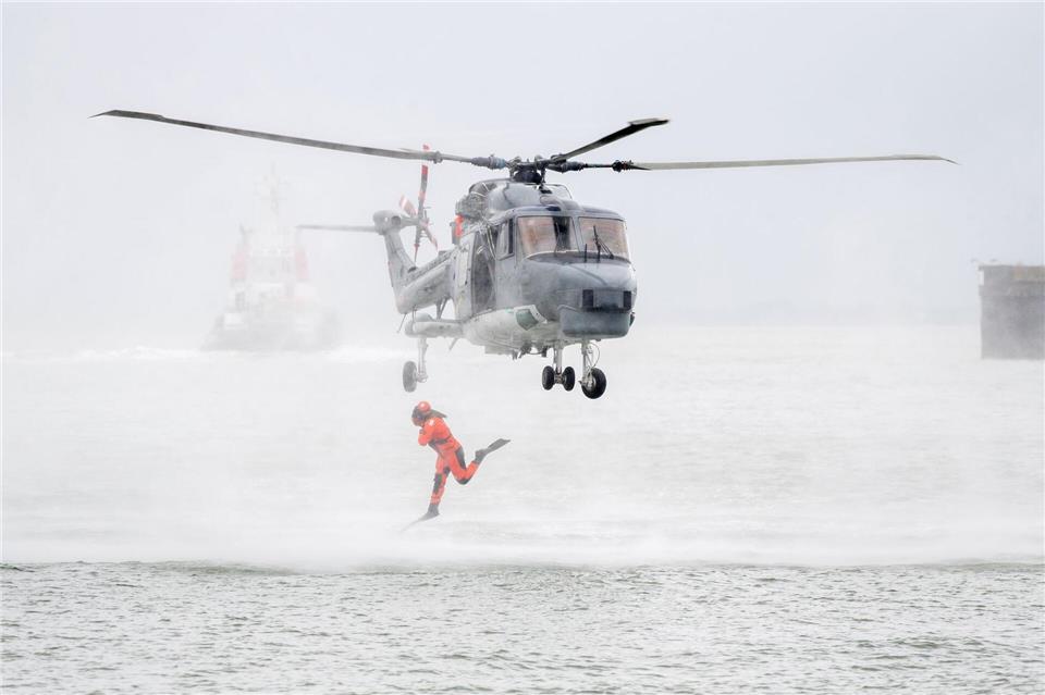 Ein Taucher springt im Rahmen einer Vorführung auf dem Marinestützpunkt Wilhelmshaven aus einem Hubschrauber.Hauke-Christian Dittrich/dpa