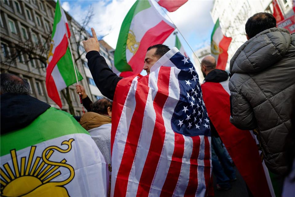Ein Teilnehmer der Düsseldorfer Iran-Demo hat sich in eine US-Flagge gehüllt. Henning Kaiser/dpa