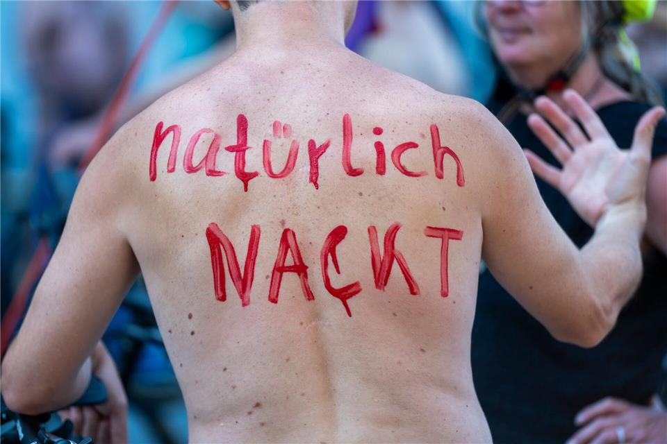 Ein Teilnehmer der Fahrrad-Demo „World Naked Bike Ride (WNBR) Berlin 2026“ hat auf dem Rücken den Schriftzug „natürlich nackt“ geschrieben.Christophe Gateau/dpa