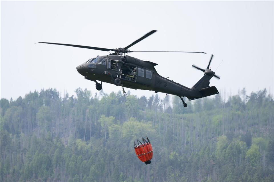 Ein Transporthubschrauber mit einem Löschwasser-Behälter beim Landeanflug auf den Flug- und Landeplatz Chribska im Nationalpark Böhmische Schweiz.Sebastian Kahnert/dpa