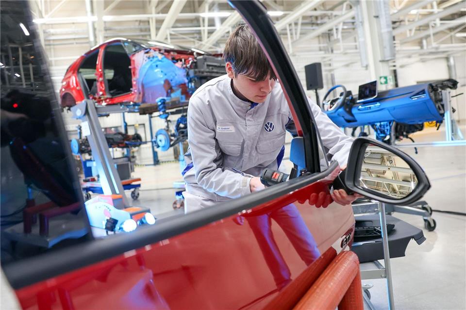 Ein VW-Mitarbeiter demontiert den Außenspiegel aus einem zerlegten VW ID.3. Künftig sollen im Zwickauer VW-Werk auf diese Weise Originalteile für die Reparatur und Aufbereitung von Gebrauchtwagen gewonnen werden. Jan Woitas/dpa