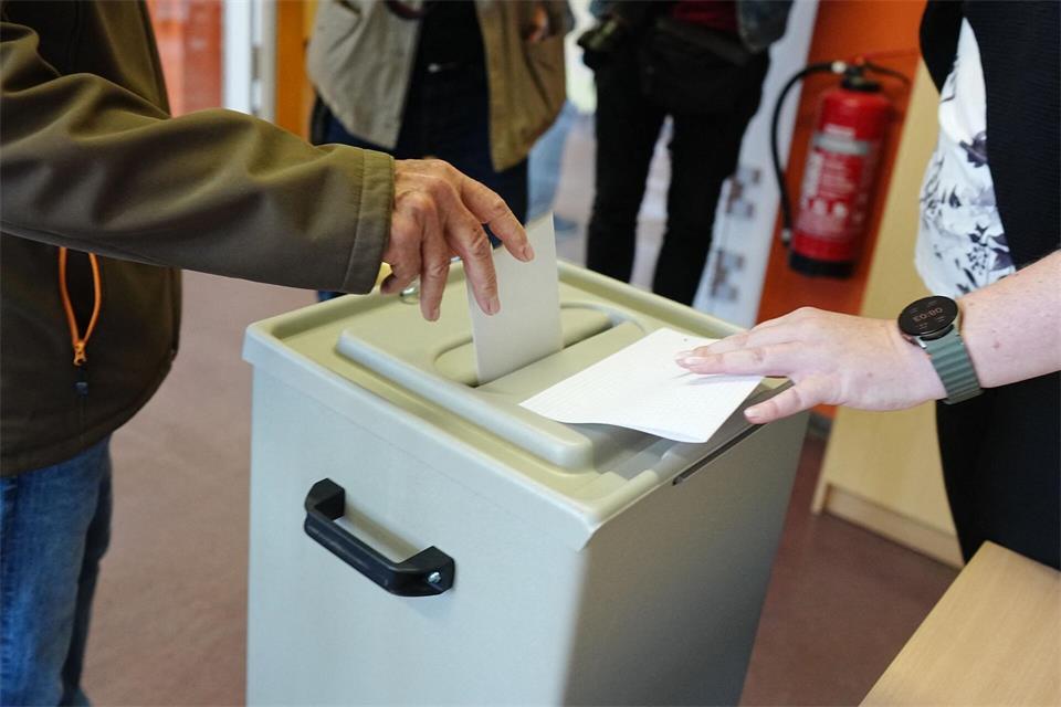 Ein Wähler wirft seinen gefalteten Stimmzettel in die Wahlurne in einem Wahllokal.Kay Nietfeld/dpa