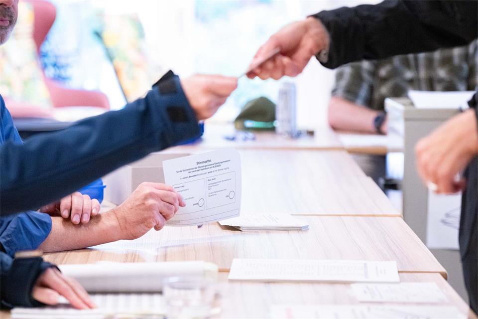Ein Wahlhelfer übergibt einer Wählerin den Stimmzettel zur Stichwahl zur Kommunalwahl in einem Bonner Wahllokal (Archivfoto)Benjamin Westhoff/dpa