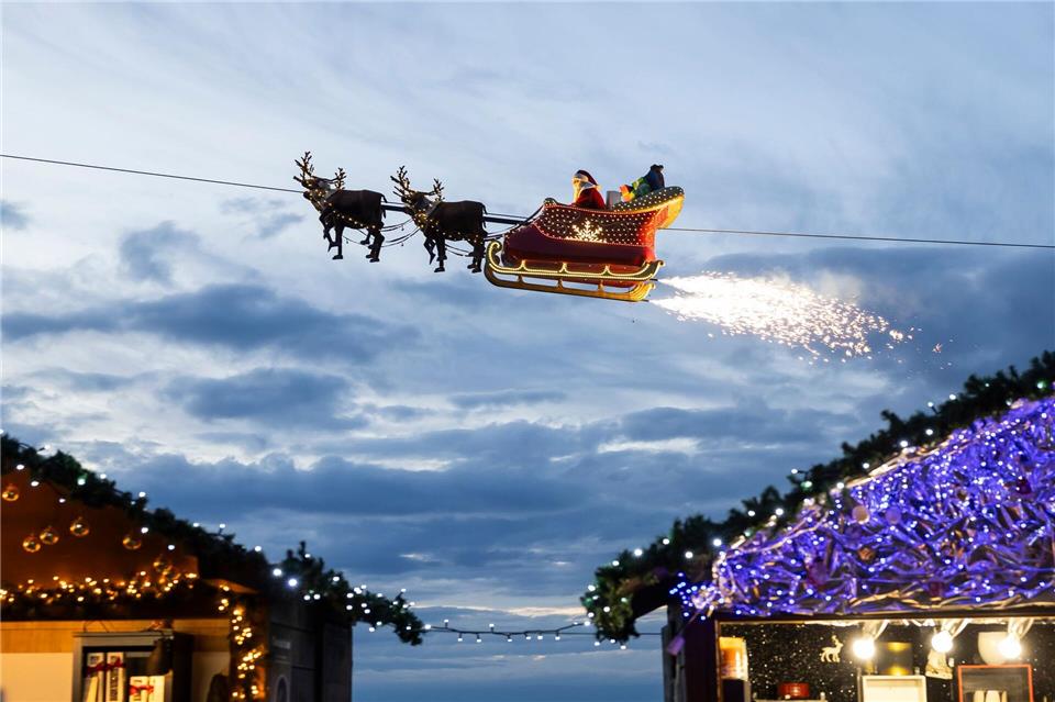 Ein Weihnachtsmann in einem fliegenden Schlitten ist in Montreux über den Weihnachtsständen vom Weihnachtsmarkt unterwegs.Cyril Zingaro/KEYSTONE/dpa