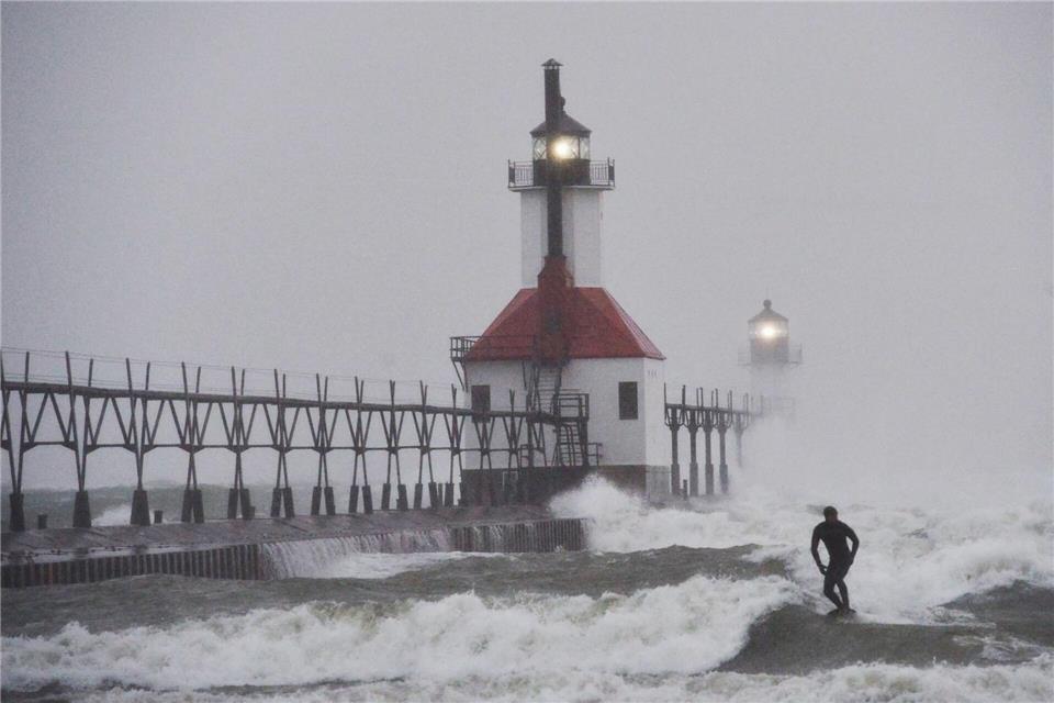 Ein Wellenreiter surft durch wehenden Schnee.Don Campbell/The Herald-Palladium/AP/dpa