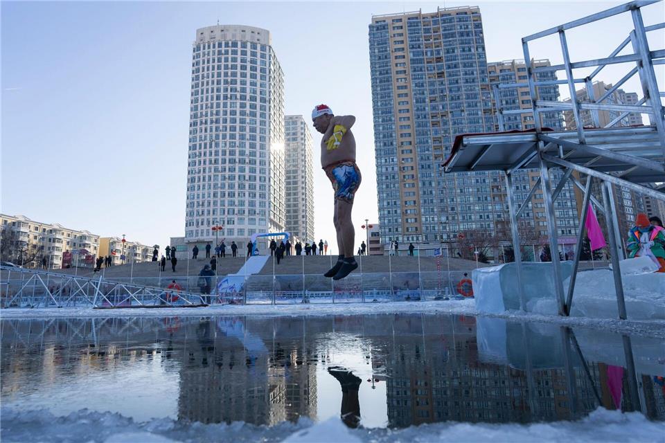Ein Winterschwimmer springt in Harbin in der chinesischen Provinz Heilongjiang ins eiskalte Wasser.Ng Han Guan/AP/dpa