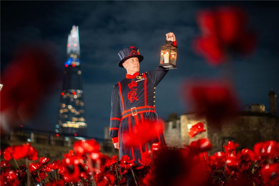 Ein Yeoman Warder (Beefeater) des Tower of London hält eine Laterne bei einer Ausstellung von Keramik-Mohnblumen im Tower anlässlich des Armistice Day.James Manning/PA Wire/dpa