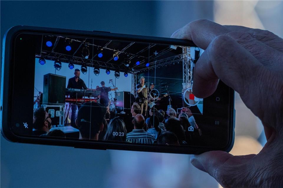 Ein Zuhörer hält das Konzert mit seinem Handy fest.  Stefan Sauer/dpa