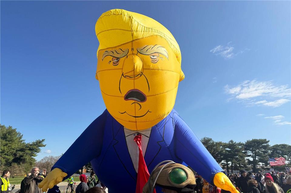 Ein aufblasbarer Ballon mit dem Abbild von US-Präsident Donald Trump ragt über eine Menschenmenge während einer „No Kings“-Demonstration.Anna Ringle/dpa