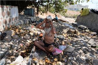 Ein heiliger Mann kühlt sich an einem heißen Tag in der indischen Stadt Jammu mit Wasser ab.Channi Anand/AP/dpa