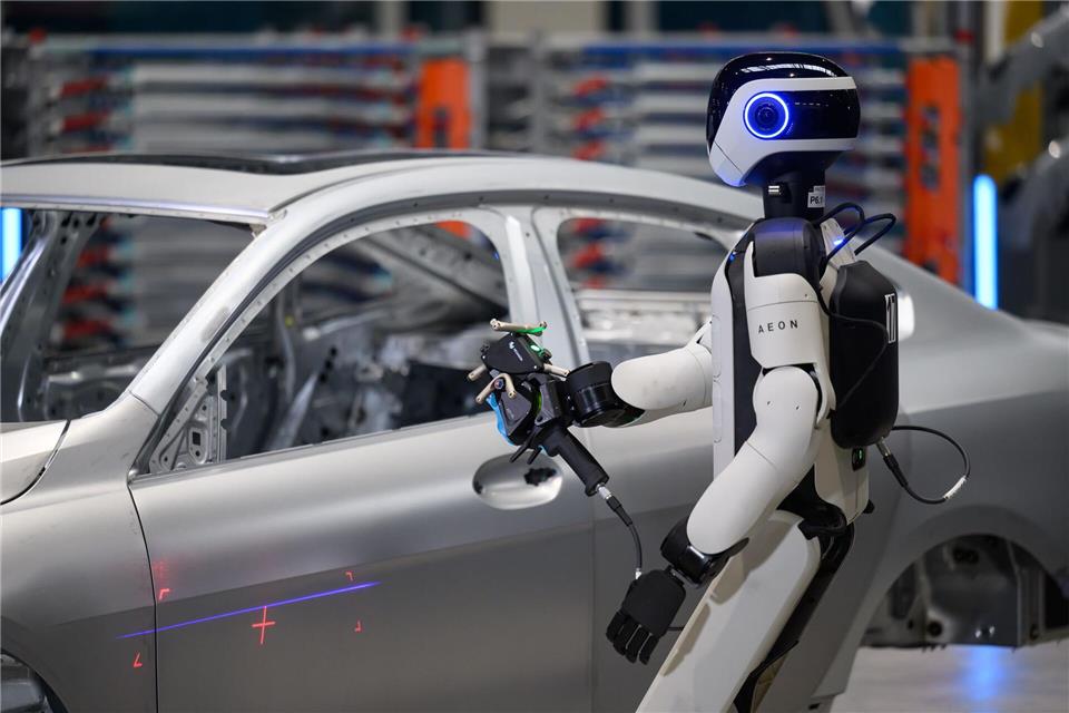 Ein humanoider Roboter prüft im BMW-Werk Leipzig eine Fahrzeugkarosserie auf Maßhaltigkeit und mögliche Fehler.Hendrik Schmidt/dpa