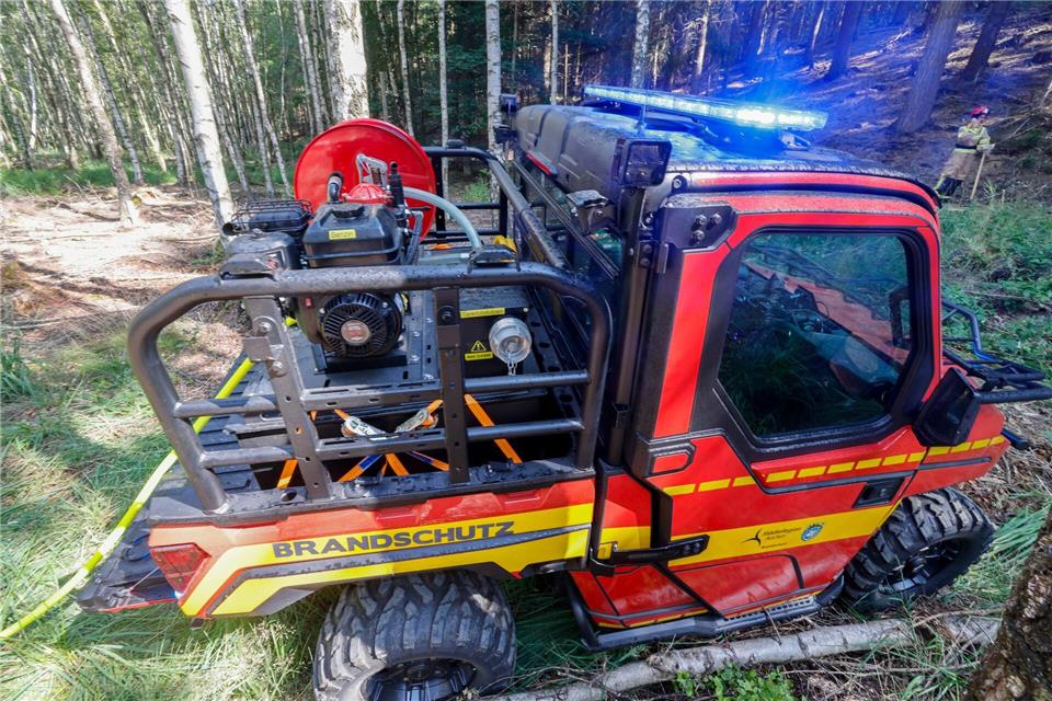 Ein kleines, wendiges Feuerwehr-Spezialfahrzeug steht in schwer zugänglichem Waldgelände. Thomas Banneyer/dpa