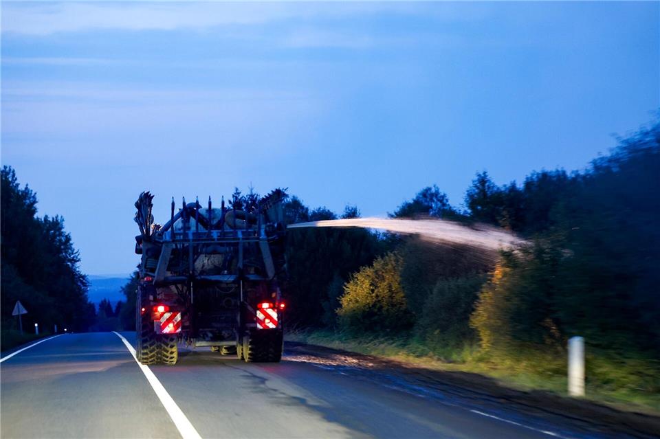 Ein landwirtschaftliches Fahrzeug wässert den Straßenrand mit Wasser aus dem Tank hinter seinem Traktor gegen die Flammen. Thomas Banneyer/dpa